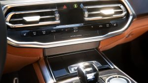 Close-up of a modern European luxury car's touchless HVAC gesture control interface in a sunlit cabin, visualizing infrared sensor baseline drift caused by extreme summer heat soak.